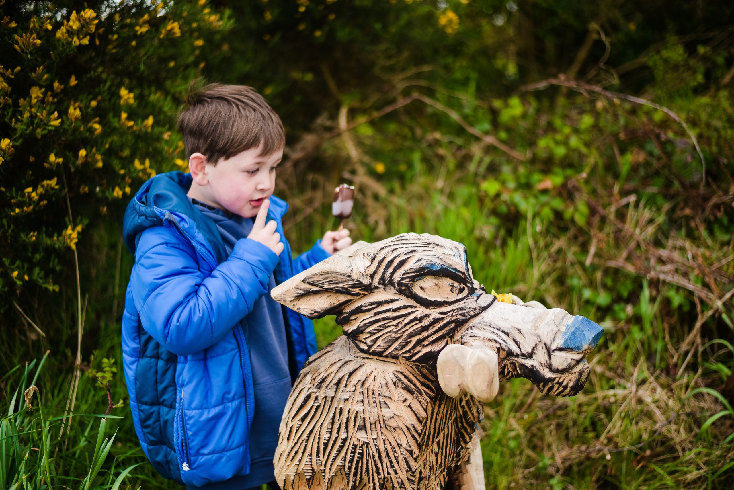 Little boy looking at wooden wolf
