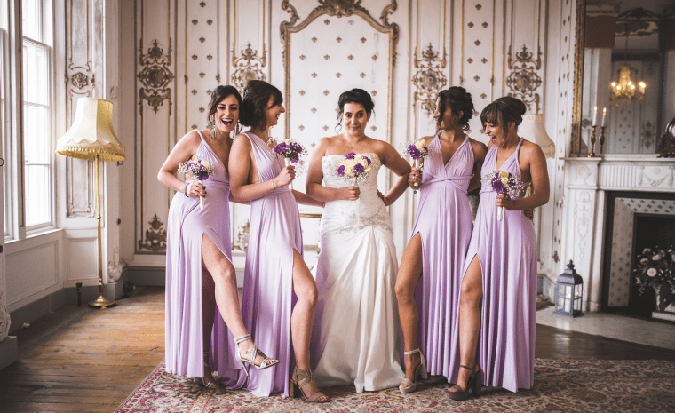 The bride and all the bridesmaids in purple dresses smiling and talking