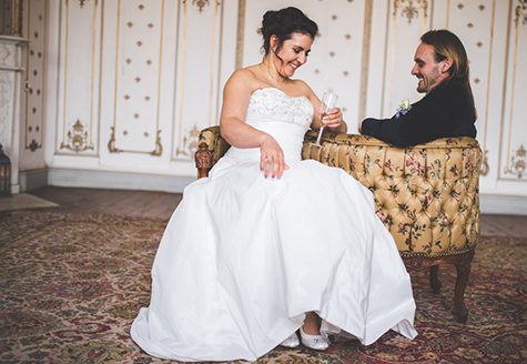 Bride and groom sitting on a couch laughing
