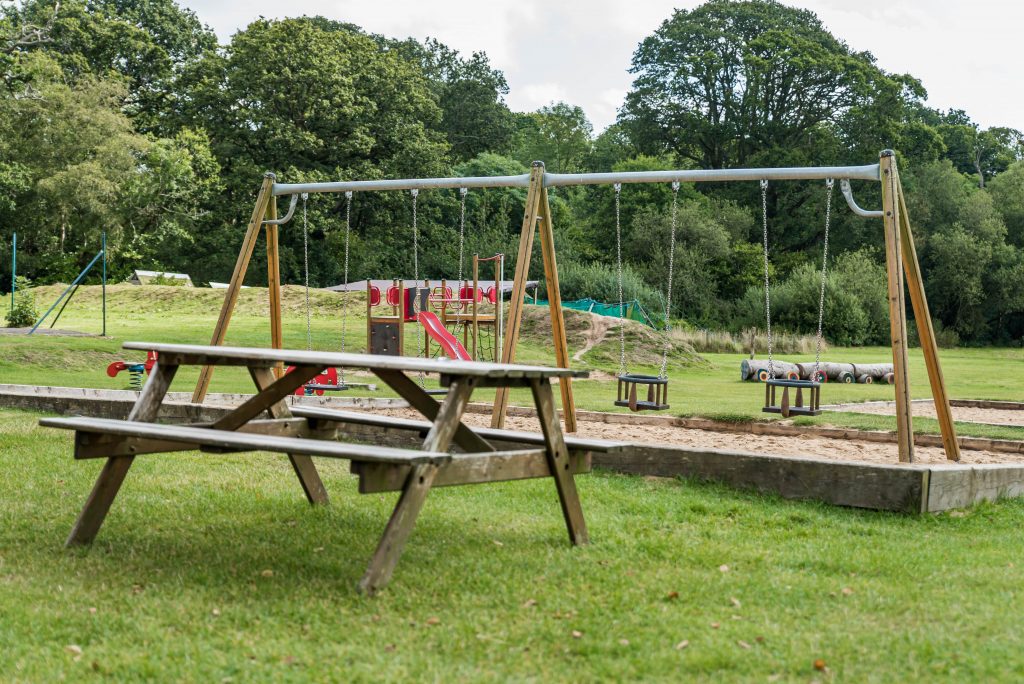Swing and playground set, with a wooden park table
