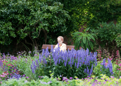 Female sitting on a bench with a beautiful garden surrounding her